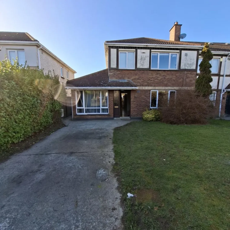 Two-story brick house with front lawn and driveway on a sunny day.