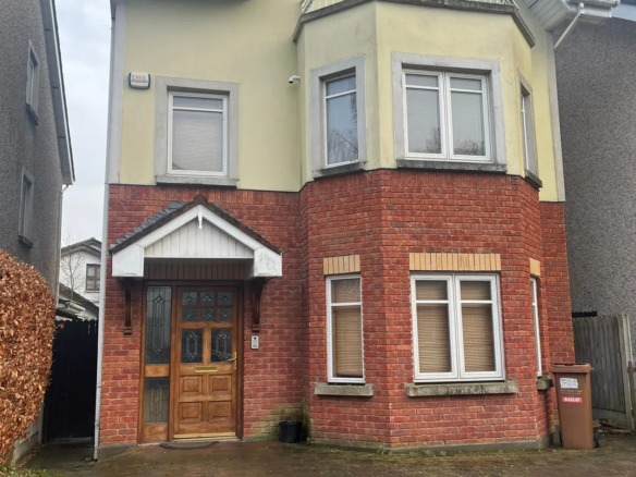 Two-story house with brick facade, bay window, balcony, and front door.