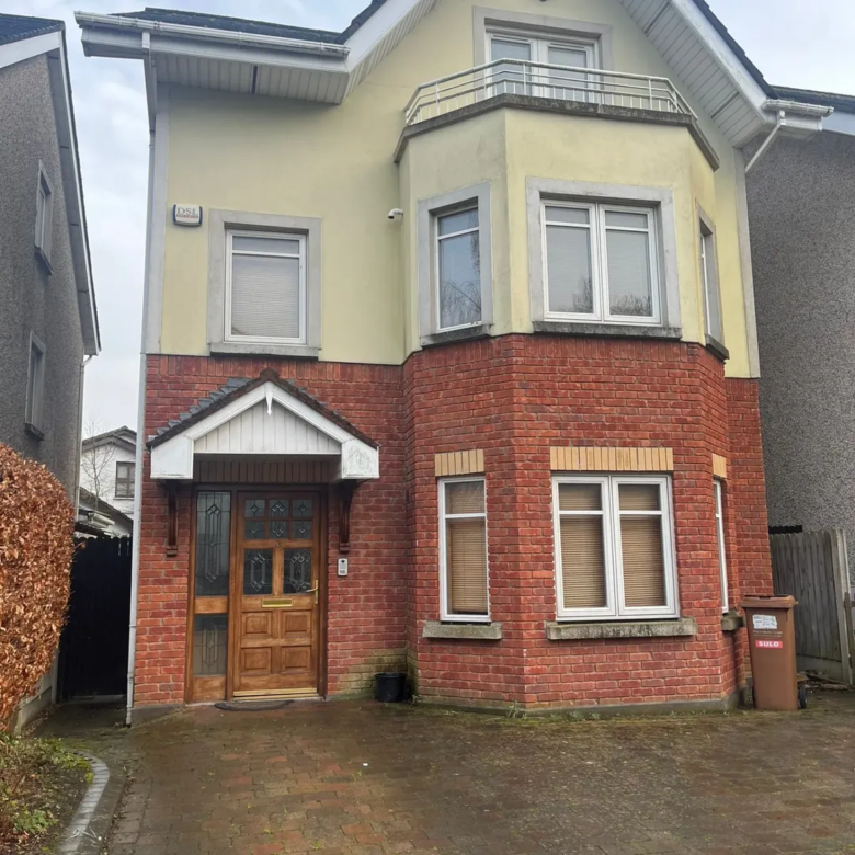 Two-story house with brick facade, bay window, balcony, and front door.