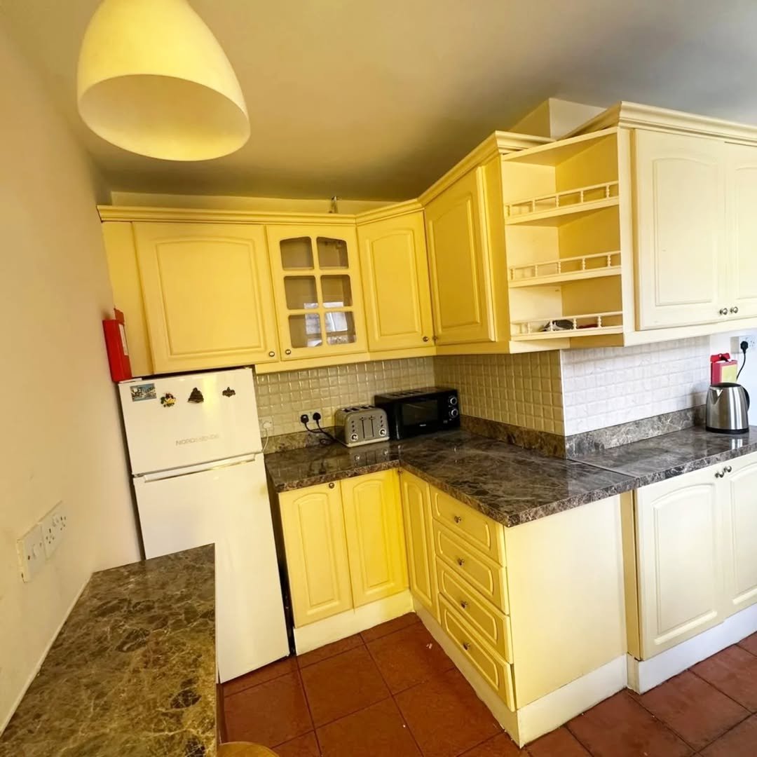 Cozy yellow kitchen with granite counters, white appliances, and warm lighting.