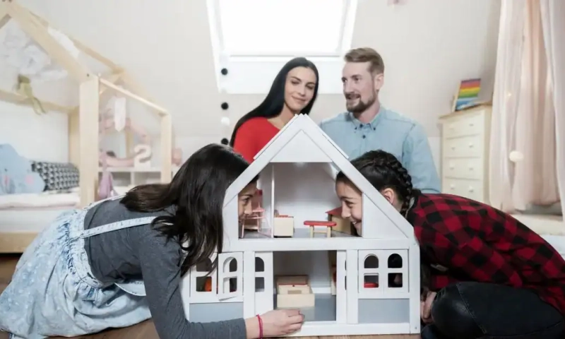 Family admiring a dollhouse in a bright room, thinking about buying a house in Dublin. – Ghar.ie property listing