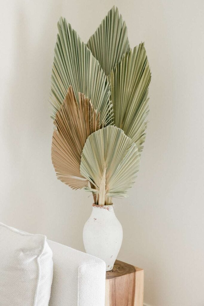 Dried palm leaves arranged in a white vase, perfect for stylish home or office decoration.
