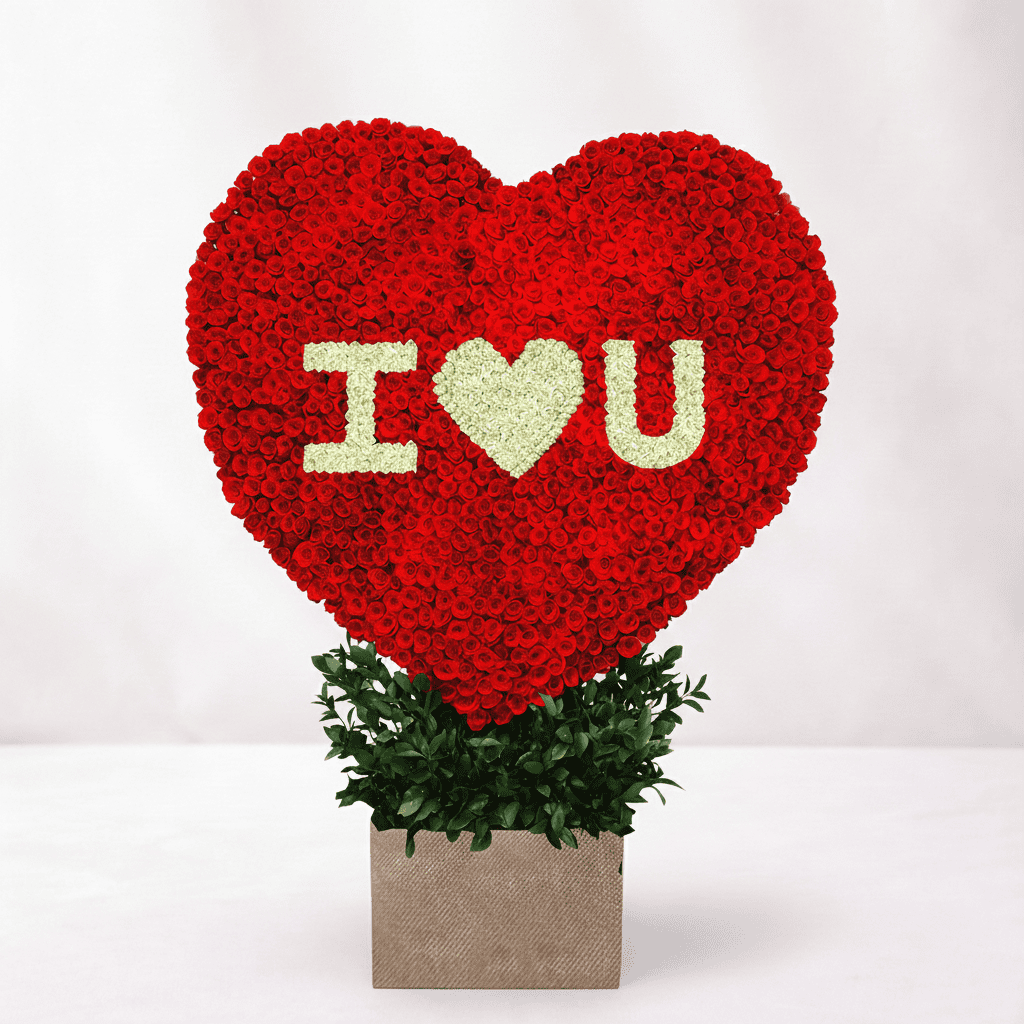 Shaped floral display with red and white roses spelling "I ♥ U" for romantic occasions.