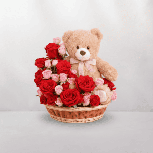 Adorable teddy bear surrounded by red and pink roses in a wicker basket, perfect for special occasio.