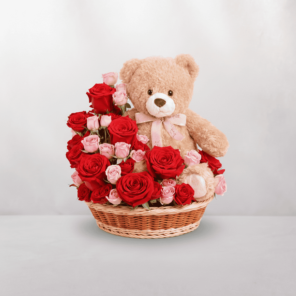 Adorable teddy bear surrounded by red and pink roses in a wicker basket, perfect for special occasio.
