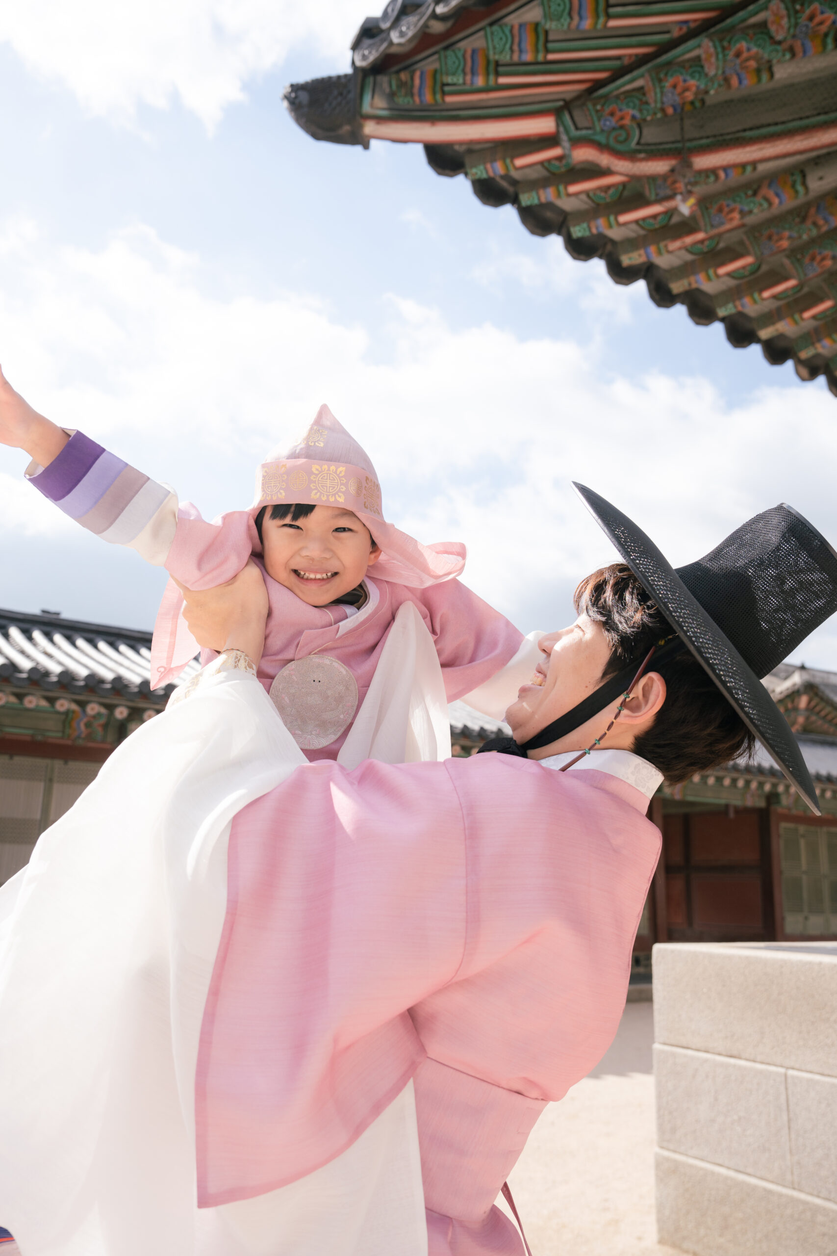 Joyful Korean family wearing traditional hanbok celebrating outdoors during golden hour for photography in Seoul Korea.