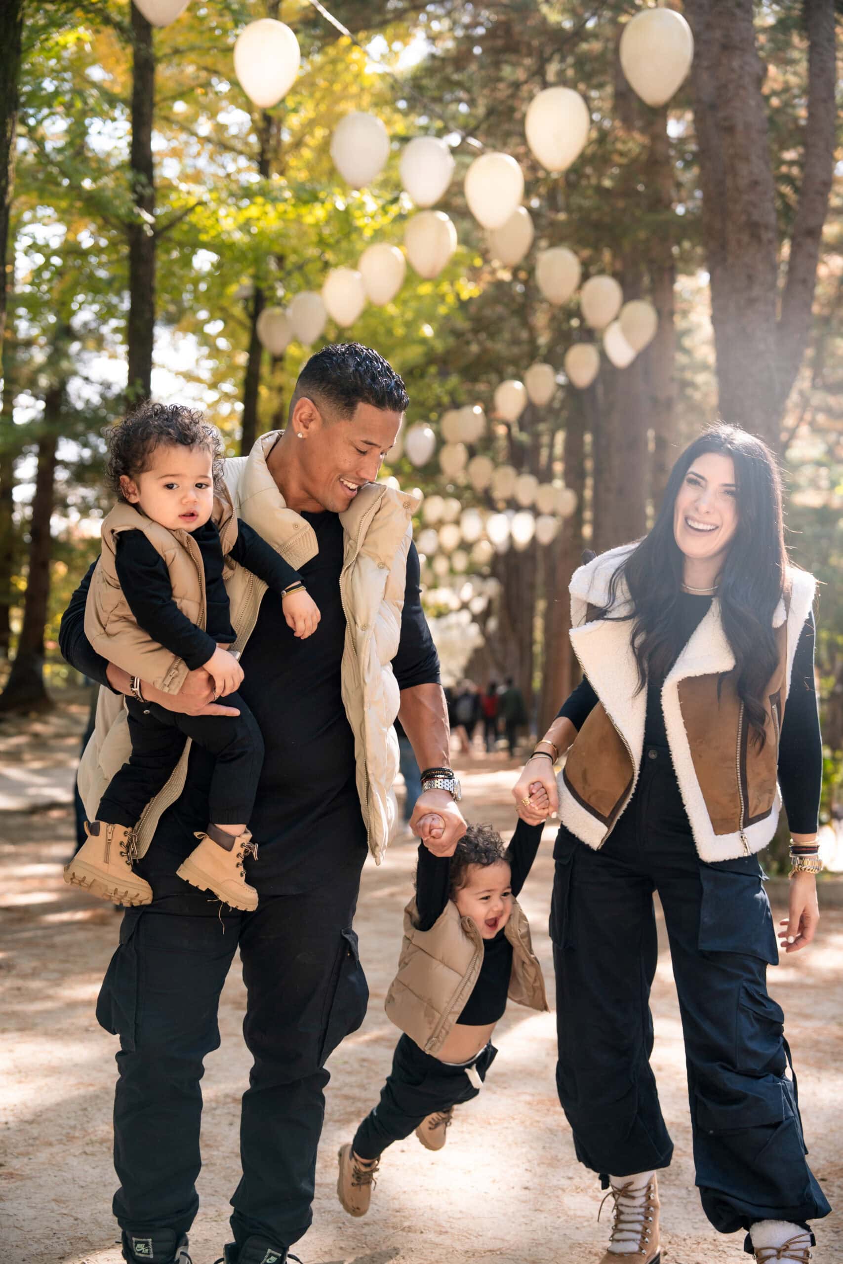 Family enjoying outdoor autumn photoshoot at Korea's scenic nature park with lantern decorations, perfect for golden hour photography.