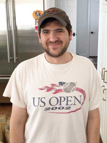 %Focuskw% | Good Tidings Plumbing, Heating &Amp; Cooling A man wearing a baseball cap and a white US Open 2002 T-shirt stands indoors, smiling at the camera.