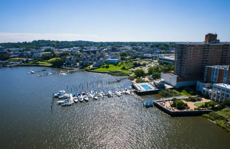 Aerial view of a waterfront marina with docked boats and adjacent apartment buildings.