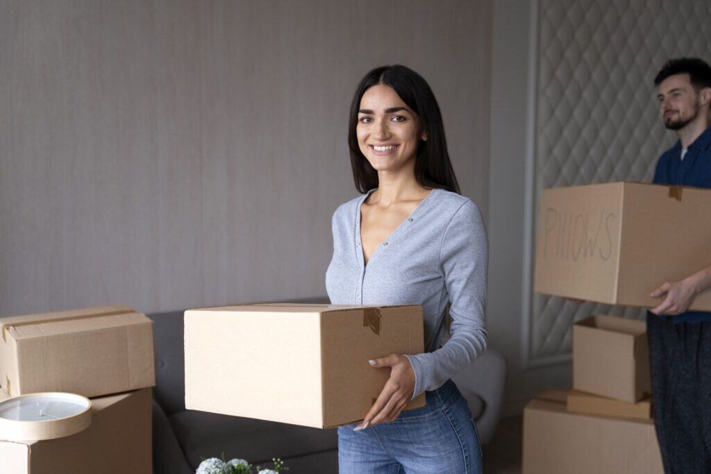 Smiling woman holding a cardboard box during packing at Green Apple Movers.