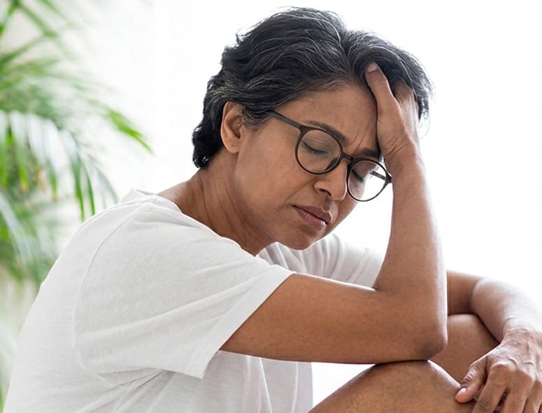 Concerned woman with head in hand, experiencing fertility issues.