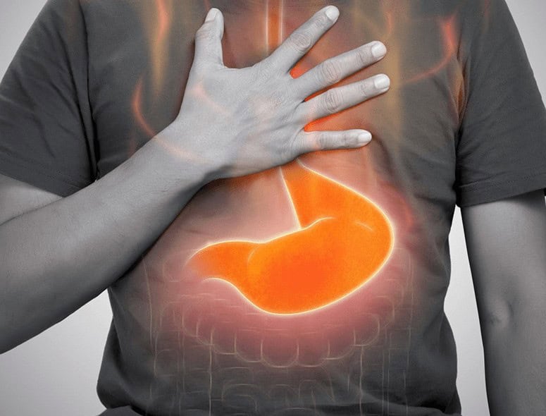 Person holding chest with stomach illustration on shirt for digestive health.