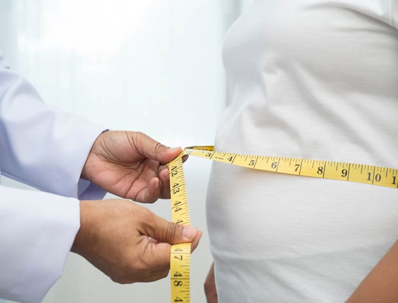 Doctor measuring pregnant woman's belly with a tape measure.