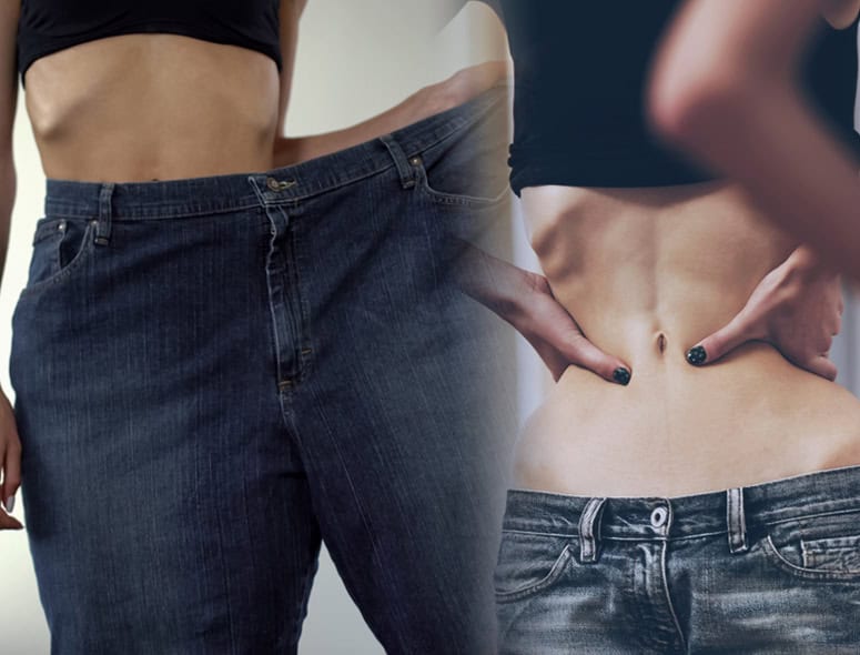 Person trying on loose jeans, indicating weight loss or body change.