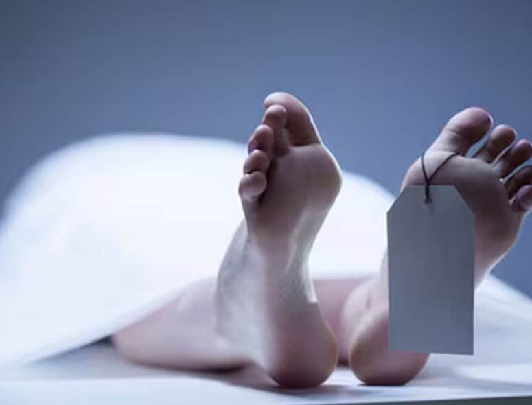 Close-up of a deceased patient's feet with a toe tag in a medical setting.