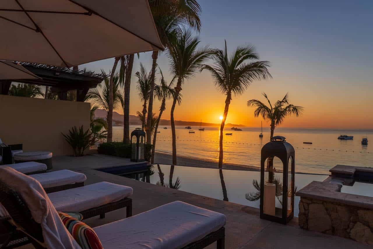 Stunning Sunset View Over The Ocean At Hacienda, Featuring A Luxurious Poolside Setting With Lounge Chairs And Palm Trees, Perfect For Relaxing In Style.