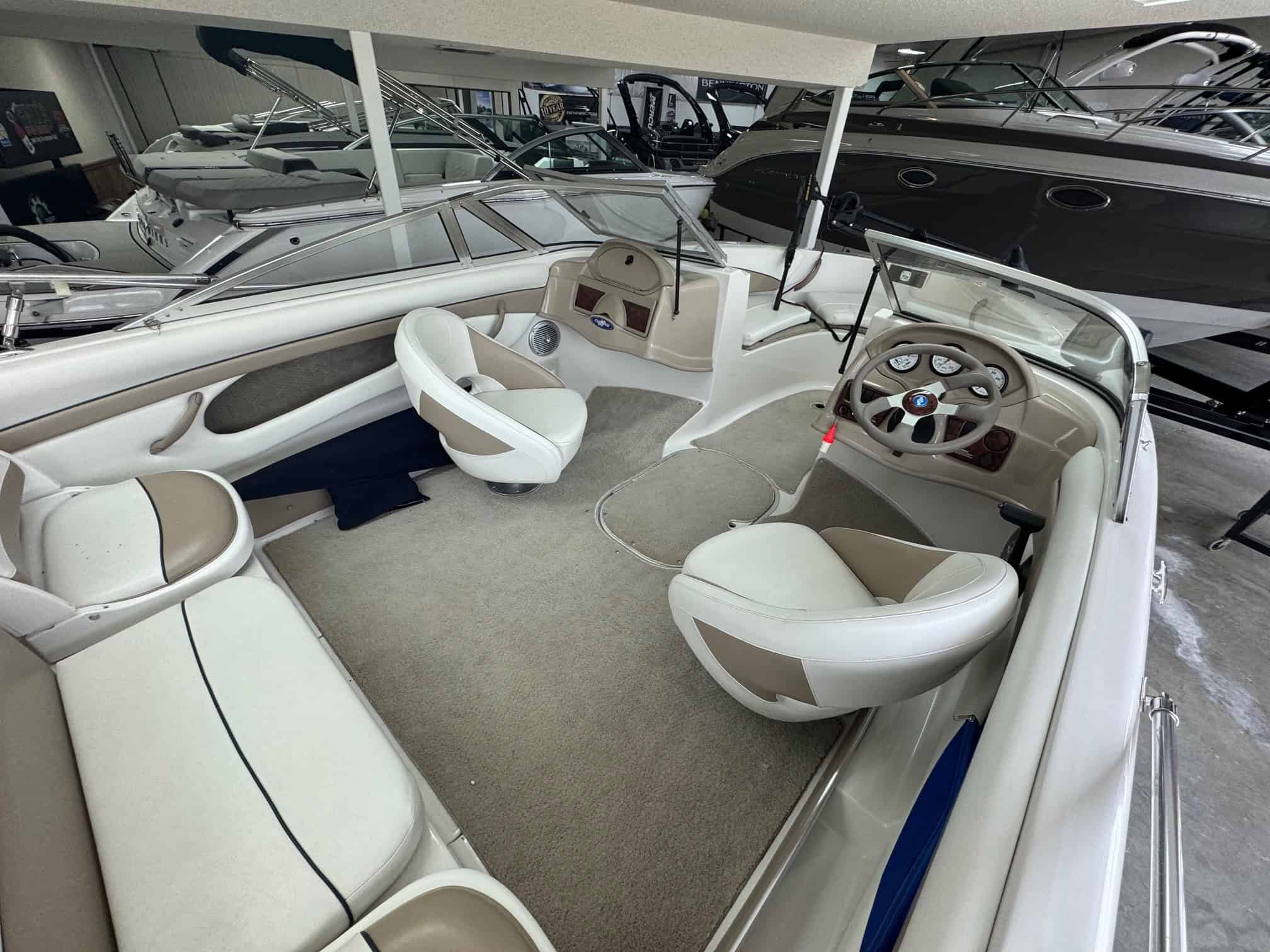 Boat interior with steering wheel and seating in a showroom.