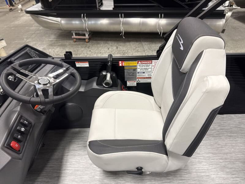 Boat captain seat with steering wheel and control panel.