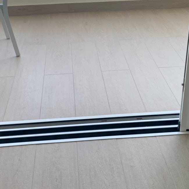 Puerta corredera de aluminio con sistema de apertura y cierre suave.