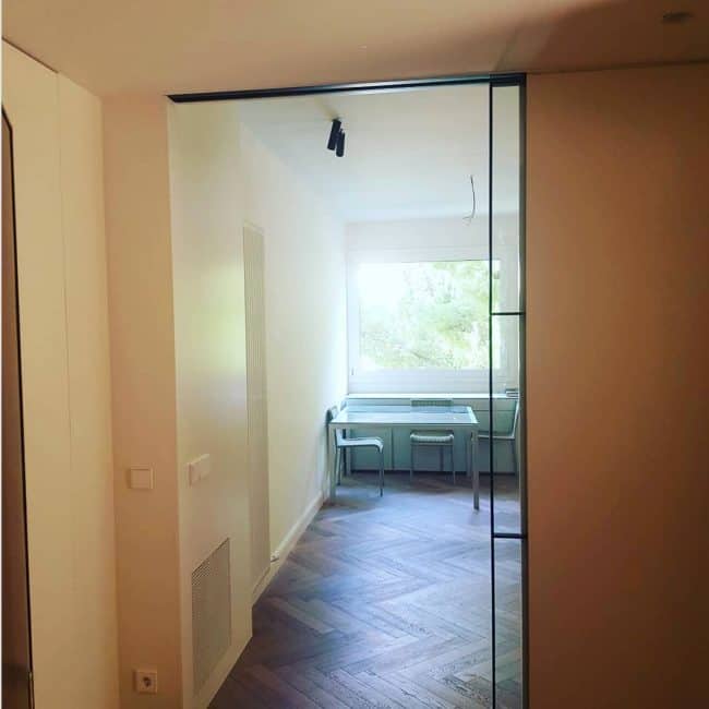 Puerta corredera de cristal en reforma de interiores para crear espacios modernos y funcionales.