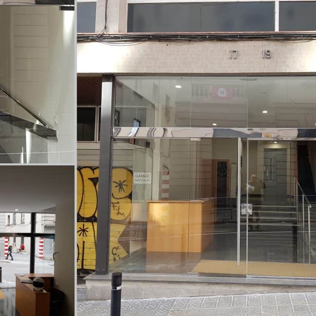 Modernización de entrada de edificio con puertas de cristal, reformas y obras de carpintería metálica.