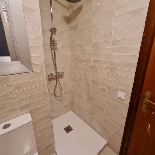 Reformas de baño con ducha moderna en vivienda en Madrid, instalación de grifería y revestimientos cerámicos de alta calidad.