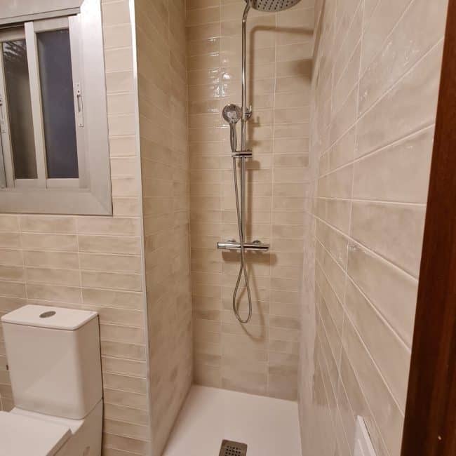Text: Rehabilitación de baño con ducha en obra para reformas integrales, estilo moderno y funcional en Barcelona.