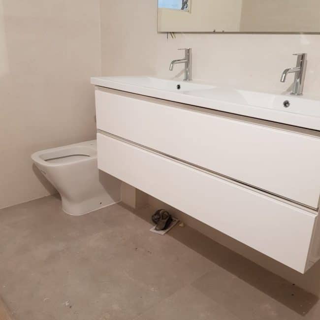 Instalación de mueble de baño moderno en reformada vivienda.