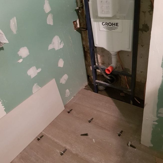 Instalación de inodoro con sistema Grohe en obra en proceso, reformas de baño, fontanería y albañilería por Hammerman Reformas.