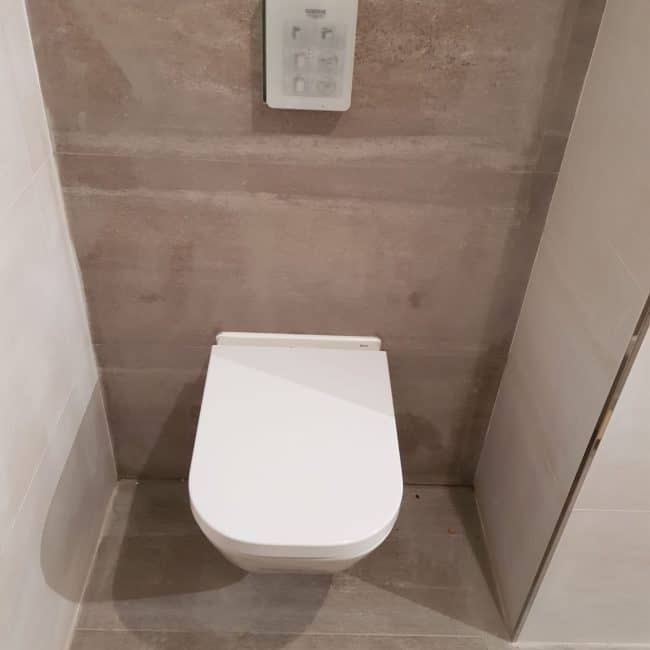 Installation de inodoro moderno con acabado en cerámica blanca para reformas de baños en Madrid.