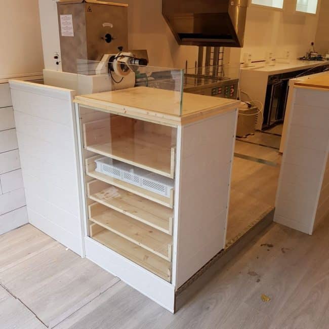 Alt: Mostrando mobiliario de madera en proceso de reforma en un local comercial.