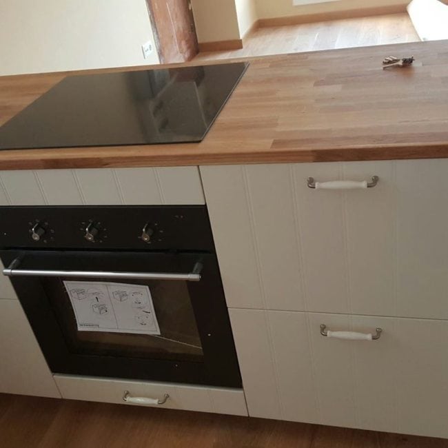 Cocina moderna con encimera de madera y horno empotrado para reformas integrales.