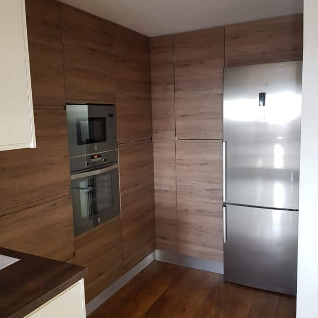 Reforma de cocina moderna con muebles de madera y electrodomésticos empotrados para un estilo funcional y elegante.