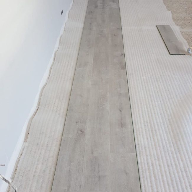 Suelo de madera en proceso de instalación en una reforma interior.