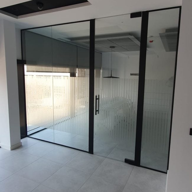 Puerta de vidrio con marco negro para oficinas modernas - Reformas y construcciones.
