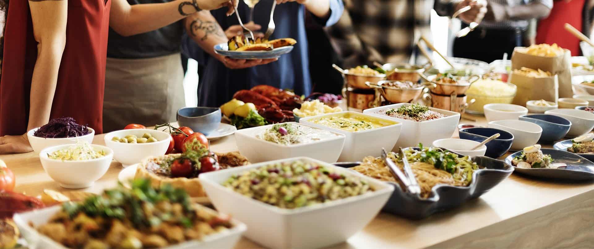 A group of people serve themselves from a variety of food at a catered buffet.