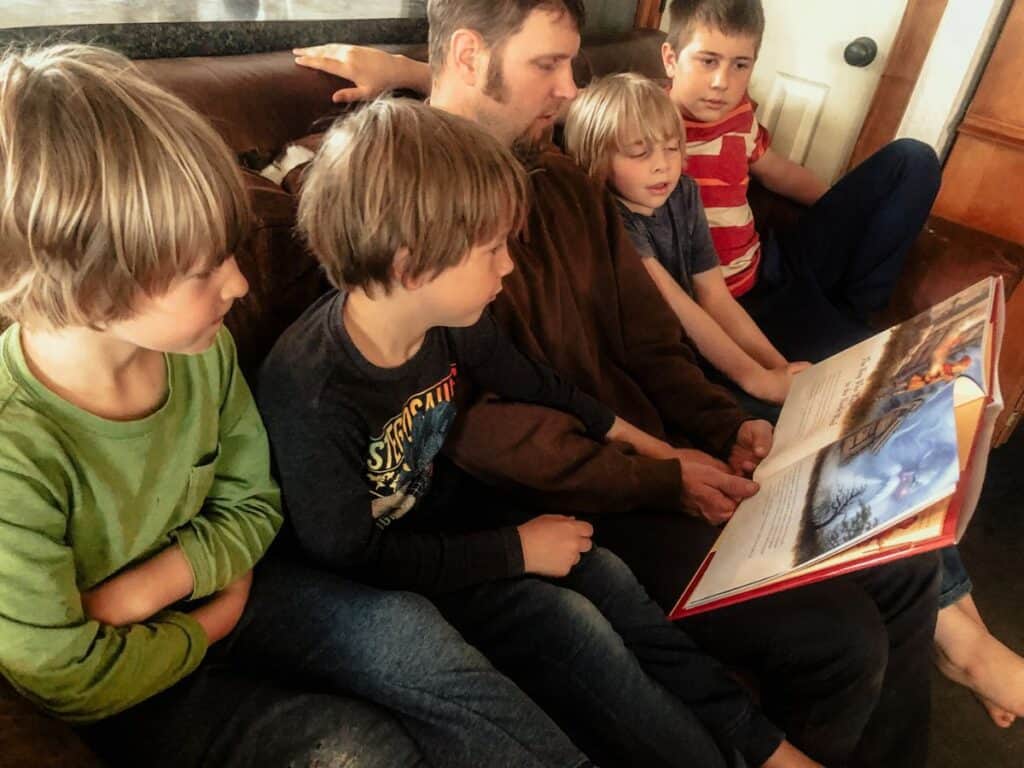 Father reading on the couch to 4 sons