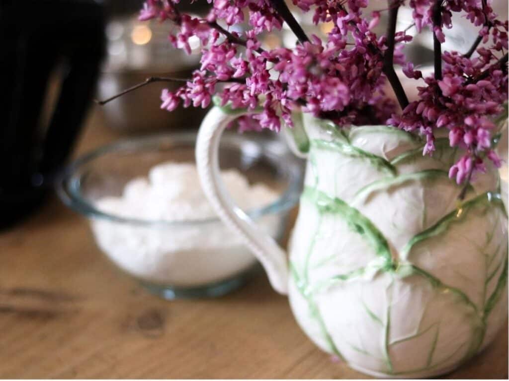 vase with redbud flowers and cake ingredients in background