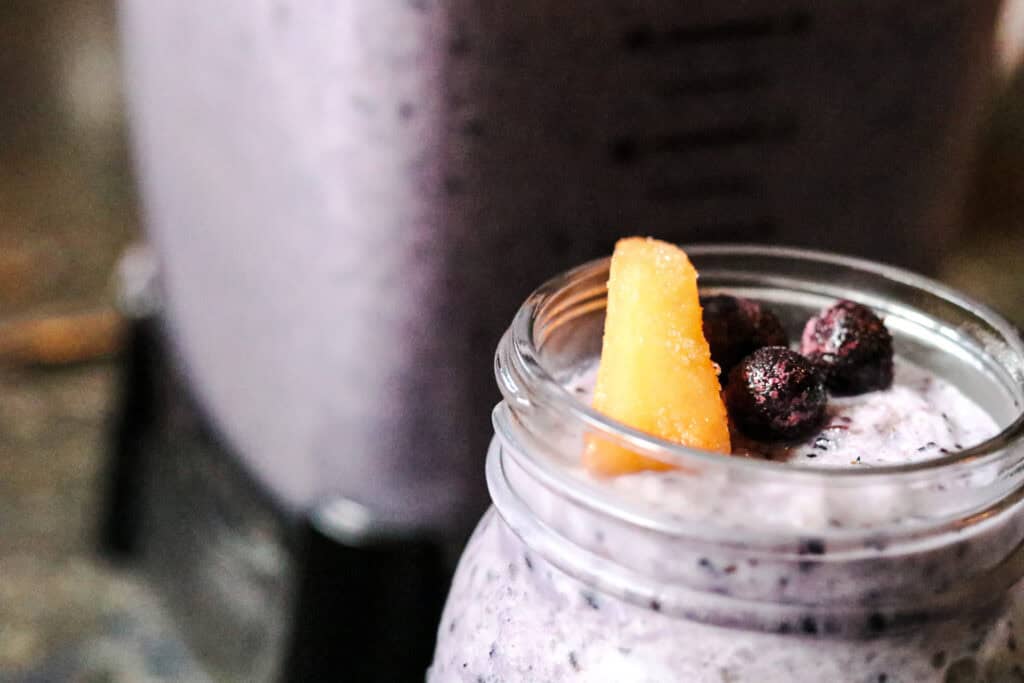 blueberry melon smoothie in a jar with piece of melon and blueberries on top