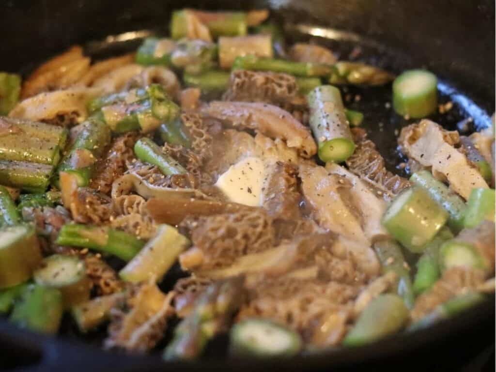 morels and asparagus cooking in a cast iron pan with butter