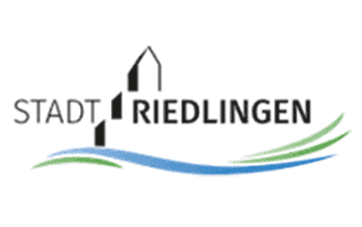 Riedlingen Logo mit dem Text STADT RIEDLINGEN, wobei das A als hohe Gebäudesilhouette stilisiert ist. Darunter befindet sich eine blaue Wellenlinie, flankiert von grünen Linien, die Natur und Wasser symbolisieren.