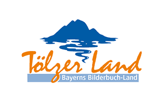 Logo mit blauer Bergsilhouette und Wasserspiegelung, darüber der Schriftzug „Tölzer Land“ in orangefarbener Schrift. Darunter ein hellblaues Rechteck mit dem Schriftzug „Bayerns Bilderbuch-Land“ in weißer Schrift. Der Hintergrund ist weiß.