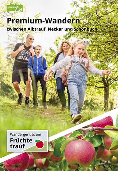 Fruechtetrauf_Booklet_Titel Eine vierköpfige Familie in Freizeitkleidung und mit Rucksäcken geht einen grasbewachsenen, von Bäumen gesäumten Weg entlang. Das Bild zeigt einen Text, der für Premium-Wandern auf der Schwäbischen Alb wirbt. Im unteren Bildbereich sind reife Äpfel zu sehen.