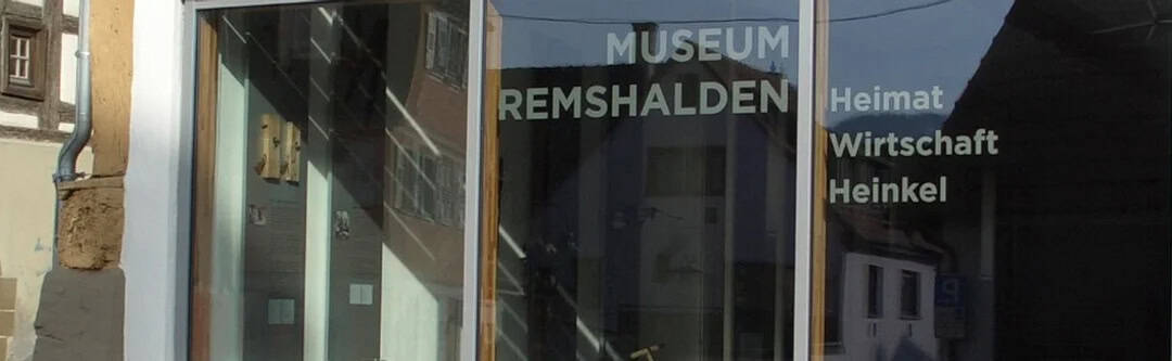 MuseumEingang_1080 Schaufenster des Museums Remshalden mit reflektierenden Fenstern mit den Worten Heimat, Wirtschaft und Heinkel.
