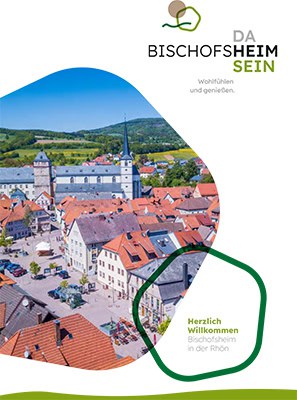 Titel_bischofsheim_imagebroschuere Luftaufnahme von Bischofsheim mit einer Kirche und bunten Dächern, umgeben von grünen Hügeln. Die Textüberlagerung umfasst BISCHOFSHEIM und Herzlich Willkommen Bischofsheim in der Rhön.