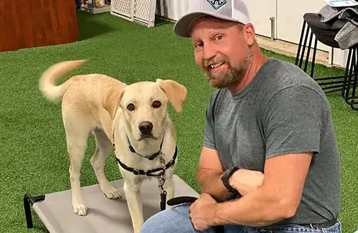 A man smiling with a service dog at High Plains K-9 Connections, demonstrating professional dog training and therapy dog services in a friendly, supportive environment.