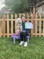 Puppy training graduation ceremony at High Plains K-9 Connections with girl holding her dog and certificate.