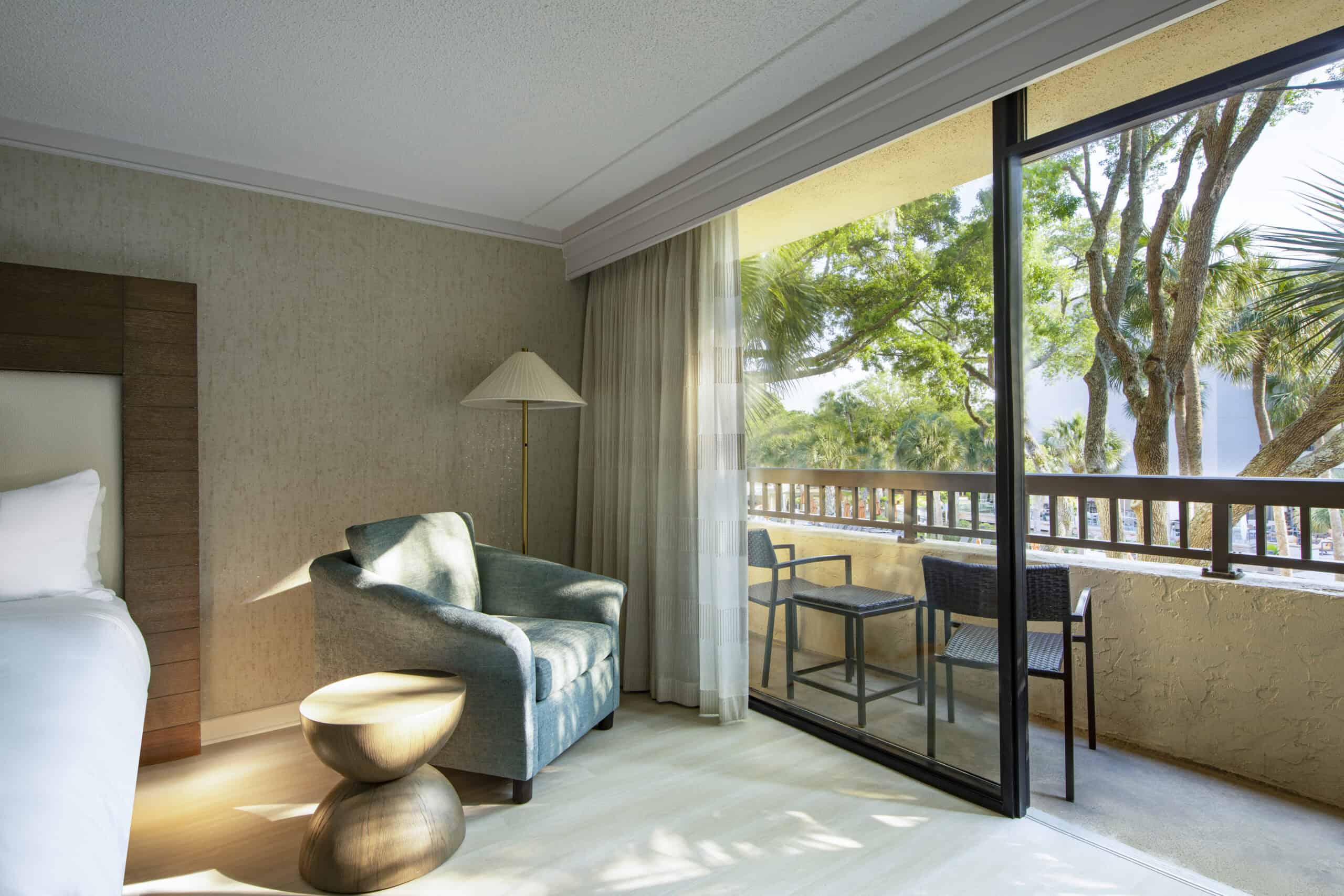 Cozy hotel room with chair and balcony.