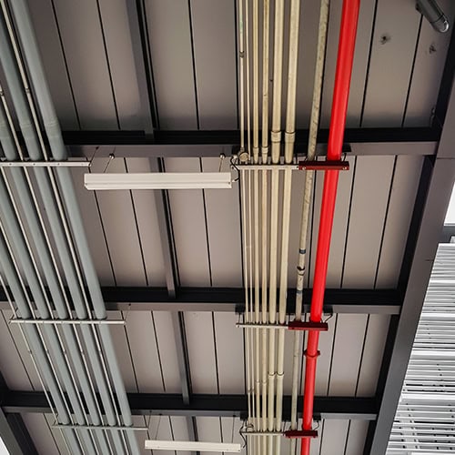 Industrial piping and electrical conduit installation at a major project site.