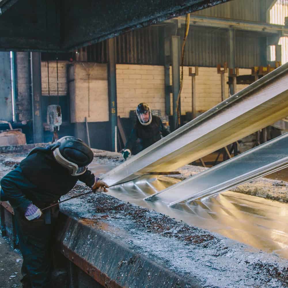 Workers pouring molten metal into molds at Hi-Tech Engineers factory.